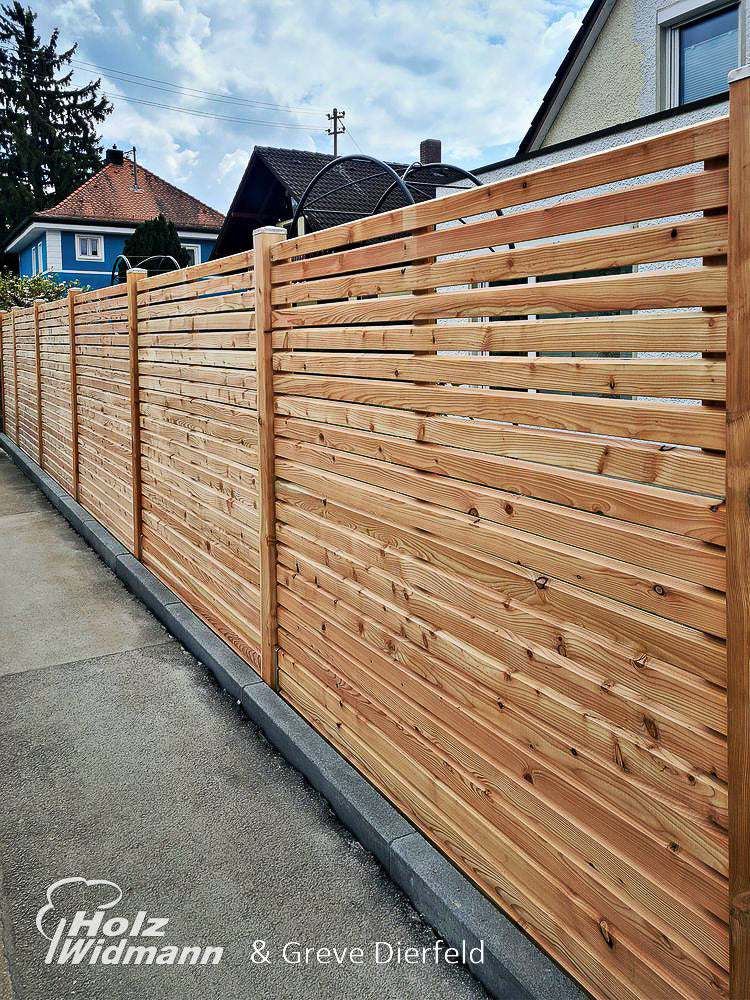 ein Holzzaun vor einem Haus