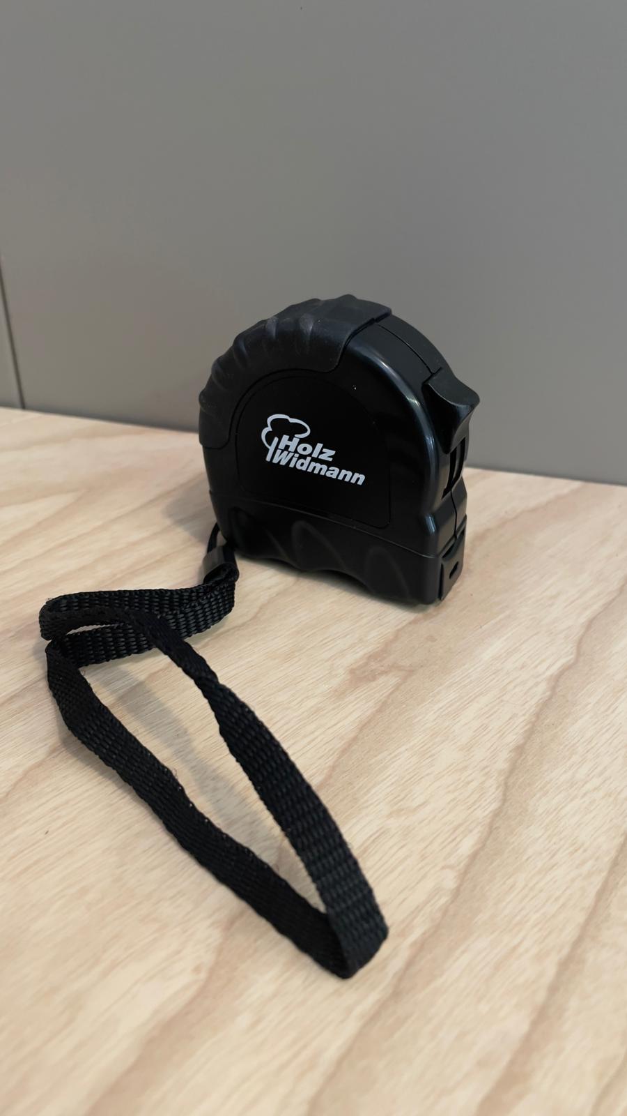 ein schwarzer Maßstab liegt auf einem Holztisch