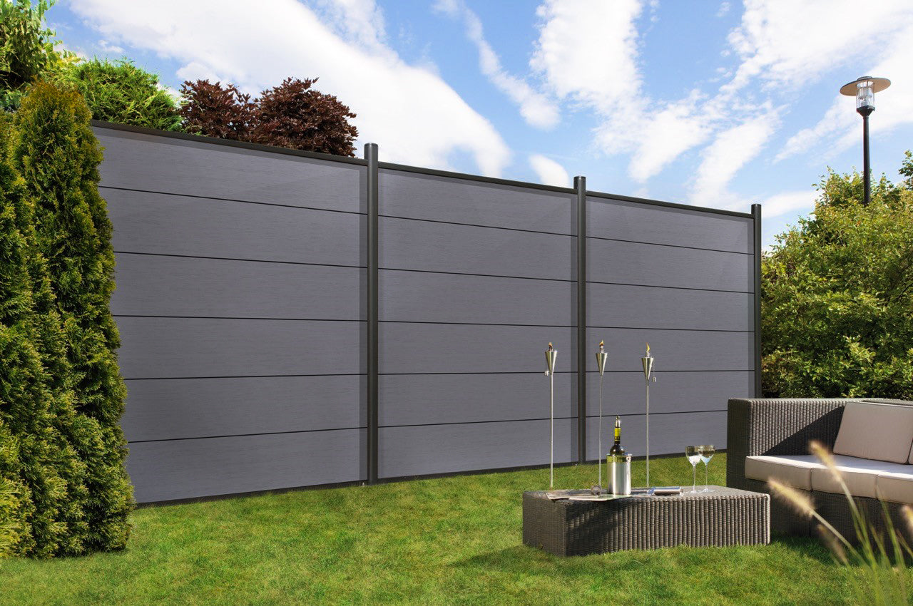 eine Couch und ein Tisch im Gras neben einem Zaun